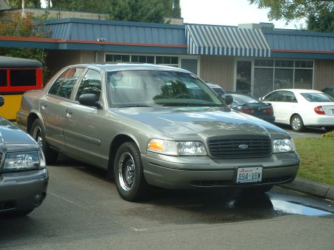 2000 Ford Crown Victoria - A 2000 Ford Crown Victoria is parked in front of a building with a blue awning.