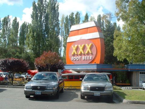 2000 Ford Crown Victoria - Two sedans are parked outside a XXX Root Beer stand on a sunny day.