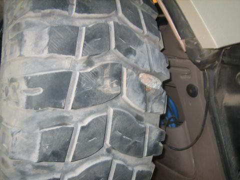 1995 Ford Bronco - A nail is lodged in the tread of a tire, likely causing a flat.