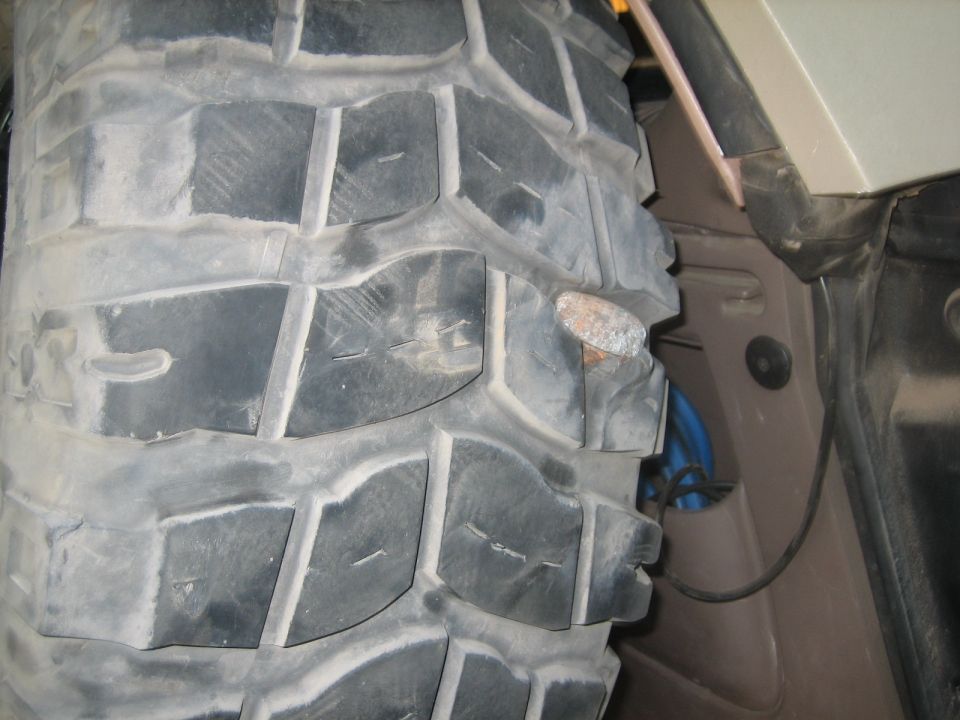 Close-up of a tire with a nail embedded in the tread