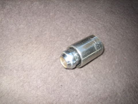1995 Ford Bronco - A close-up view of a lug nut and a socket, resting on a textured surface.