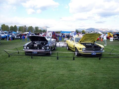 1972 Ford Ranchero - Two classic Ford Mustangs, a yellow Mach 1 and a black convertible, displayed with their engines visible at an outdoor event.