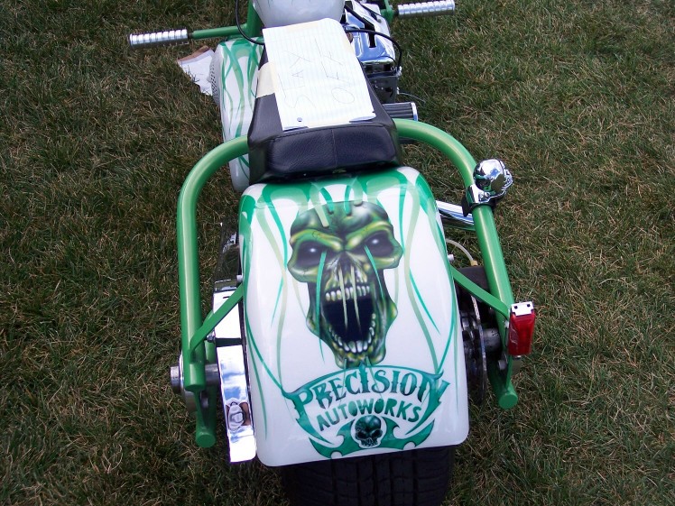 Rear view of a custom motorcycle with green skull graphics and "PRECISION AUTOWORKS" text