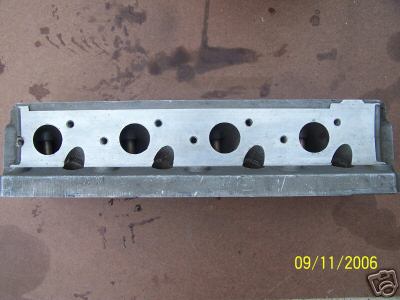 1972 Ford Ranchero - A metal engine cylinder head is shown resting on a surface with oil stains.