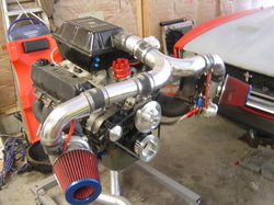 1972 Ford Ranchero - Engine assembly on a stand, ready for installation. A portion of a red vehicle is visible in the background.
