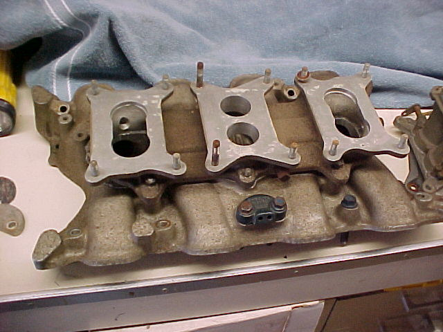 Close-up of an engine intake manifold with multiple carburetor mounting points