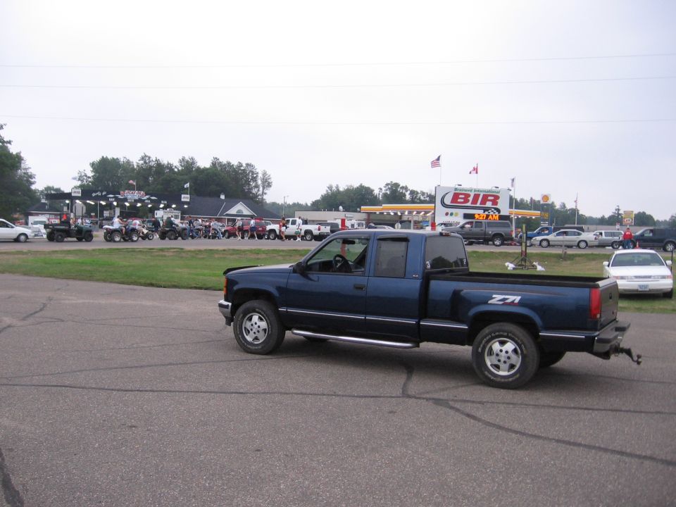 Dark blue Chevrolet extended-cab Z71 pickup, side view, in a paved lot near a racetrack