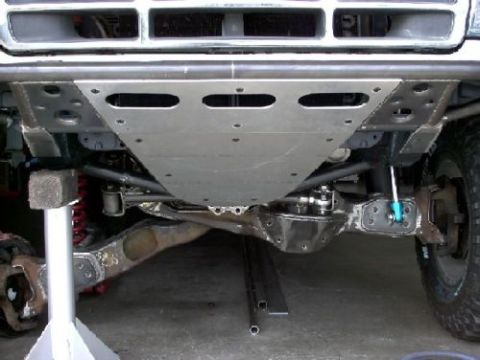 1984 Ford Bronco - The undercarriage of a vehicle is shown, custom skid plates and suspension modifications.