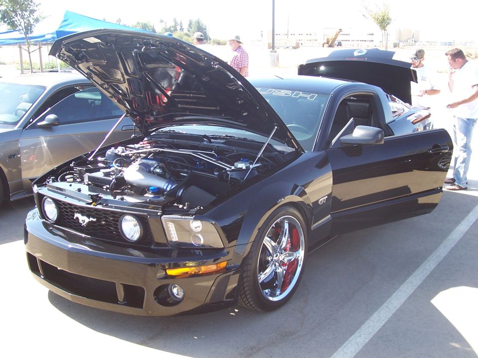 Black Ford Mustang GT with hood and door open, chrome wheels with red calipers