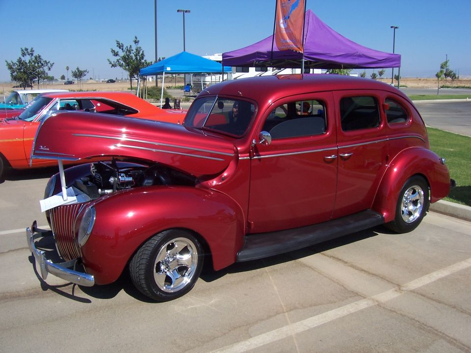 Red sedan with hood open, chrome wheels, and side trim