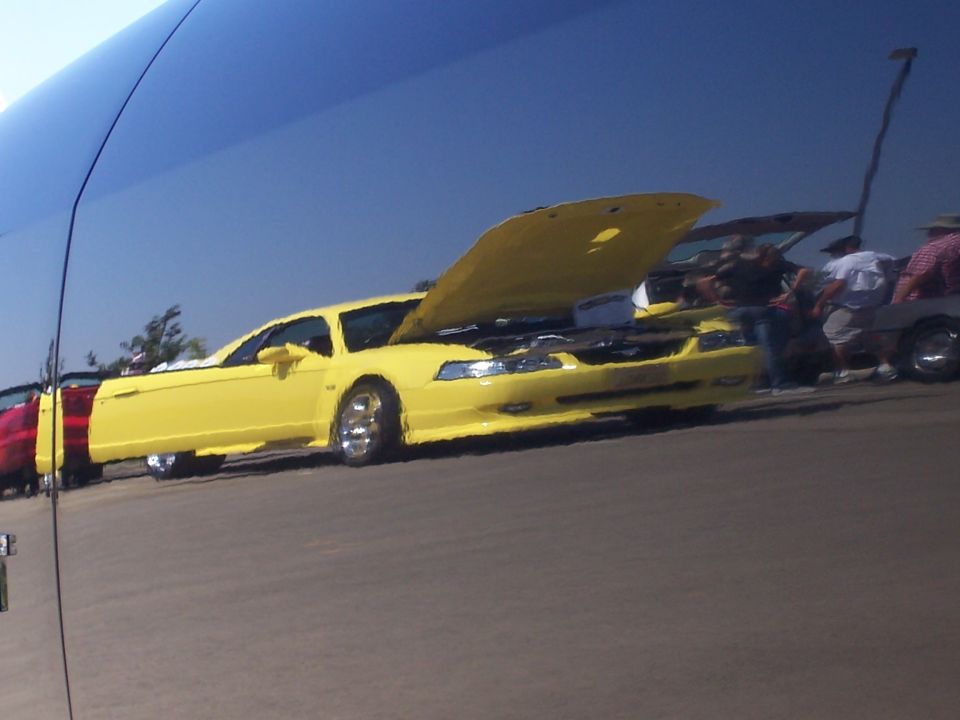Yellow 2000s Ford Mustang with hood open, parked at a car show