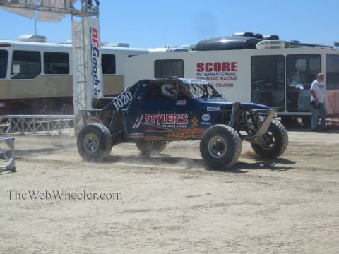 1990 Ford Bronco - blue off-road buggy numbered 1020 lettered Stylers Collision Repair drives past the SCORE media center.