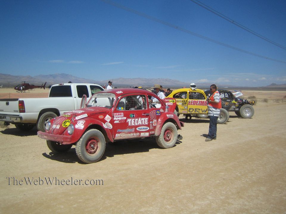 Red Tecate Baja bug and yellow buggy lined up on desert road