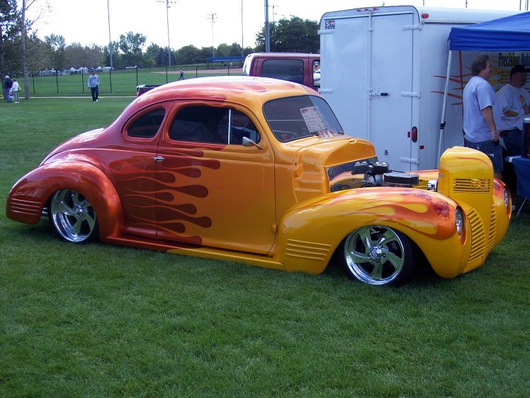 Custom hot rod with orange and yellow flame paint, lowered suspension, and exposed engine