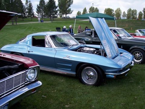 1972 Ford Ranchero - Light blue 1963 Corvette Sting Ray coupe at a car show, hood open revealing engine bay.