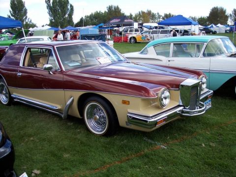 1972 Ford Ranchero - A two-tone coupe with distinctive chrome grille and wire wheels parked on grass at an outdoor event.