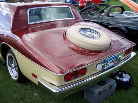 1972 Ford Ranchero - A two-tone red and tan coupe with a continental spare tire on its trunk is parked on grass next to other vehicles.