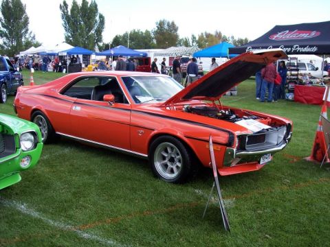 1972 Ford Ranchero - An orange AMC Javelin is displayed at an outdoor car show with its hood open, revealing the engine compartment.