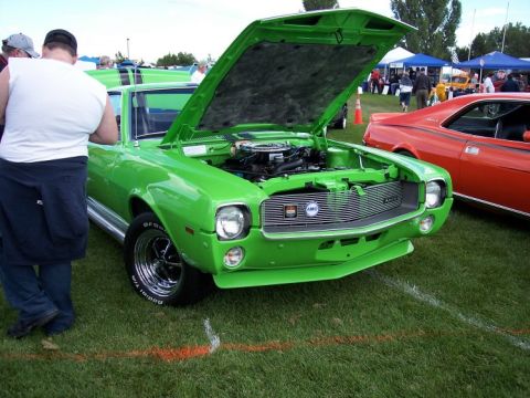 1972 Ford Ranchero - A bright green 1970 AMC Javelin is displayed with its hood open at an outdoor car show.