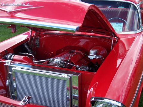 1972 Ford Ranchero - The engine bay of a red car is displayed with the hood open, revealing chrome accents and the engine components.