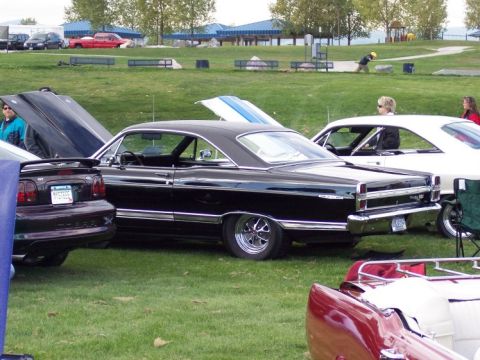 1972 Ford Ranchero - A black coupe with extensive chrome trim and custom wheels is parked on grass, viewed from the rear.