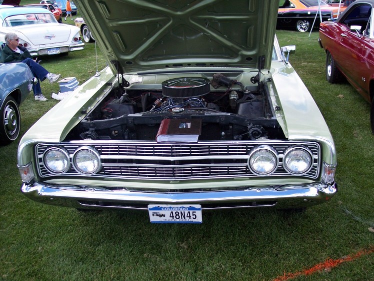Light green 1970 Ford Ranchero front view, hood open, showing engine and a book