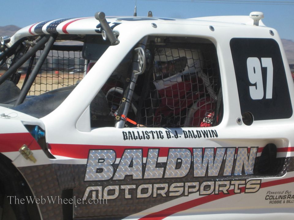 Close-up of white Baldwin Motorsports off-road truck number 97 cab with helmeted driver