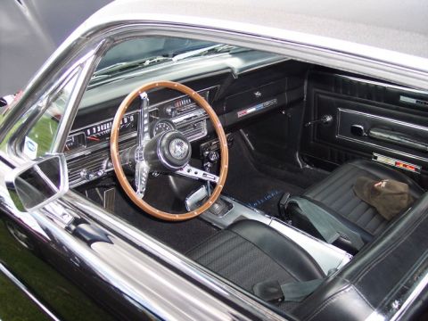 1972 Ford Ranchero - The interior of a classic car features a wood-rimmed steering wheel and black vinyl seats.