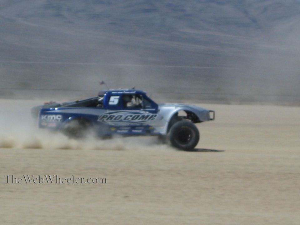 Blue and silver Pro Comp off-road race truck number 5 racing in desert