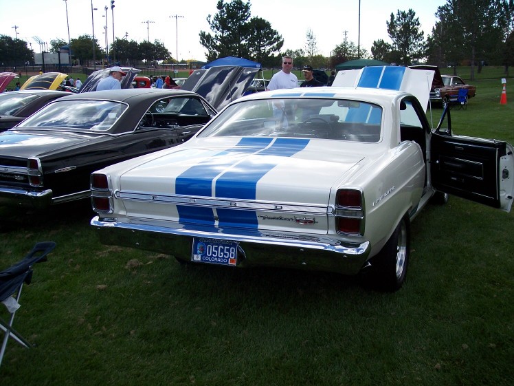 1970 Ford Torino GT with blue stripes on rear, driver door open. Another car is to the left