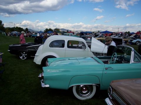 1972 Ford Ranchero - A turquoise 1955 Ford Thunderbird convertible is parked next to a white sedan at an outdoor car show.