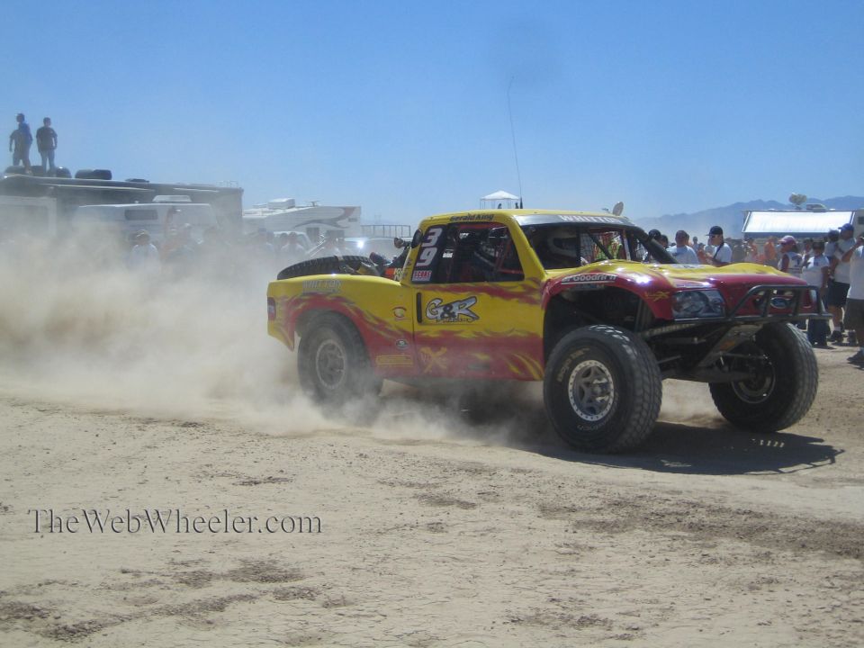 Yellow and red flame off-road race truck launching from start in dust