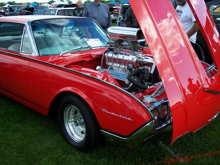 Red 1960 Ford Thunderbird with hood open showing a supercharger and V8 engine. "Thunderbird" script visible on fender