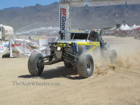 1990 Ford Bronco - white and yellow open-wheel off-road race buggy numbered 118 kicks up dust under a BFGoodrich banner.