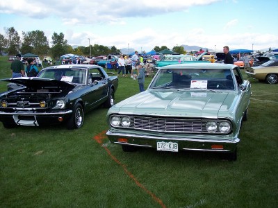 1972 Ford Ranchero - Two classic cars, a light green coupe and a dark green coupe, are displayed on a grassy field at an outdoor event.