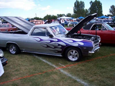 1972 Ford Ranchero - A custom 1966 El Camino with flame graphics and open hoods is displayed at an outdoor car show.