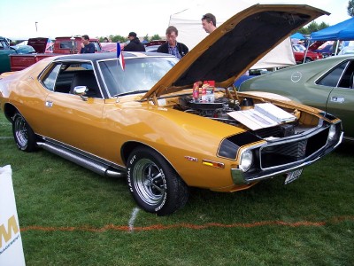 1972 Ford Ranchero - A gold muscle car with its hood open sits on display at an outdoor car show.