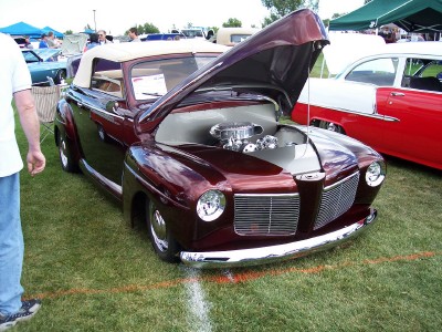 1972 Ford Ranchero - A maroon convertible with its hood open is displayed on a grassy field next to a red and white car.