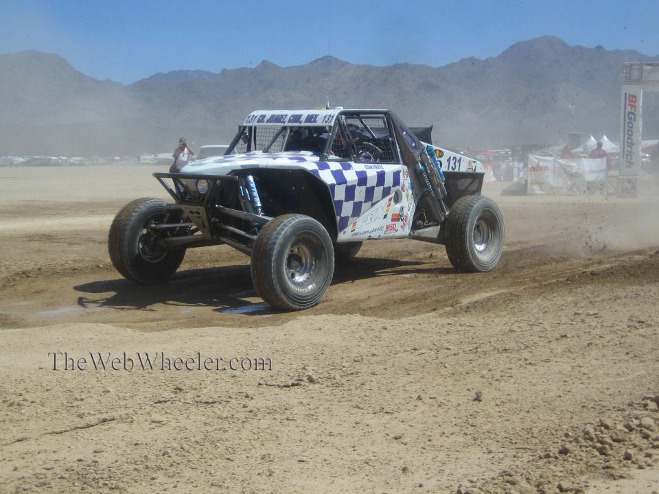 Blue and white checkered off-road race buggy number 131 cornering in desert dirt