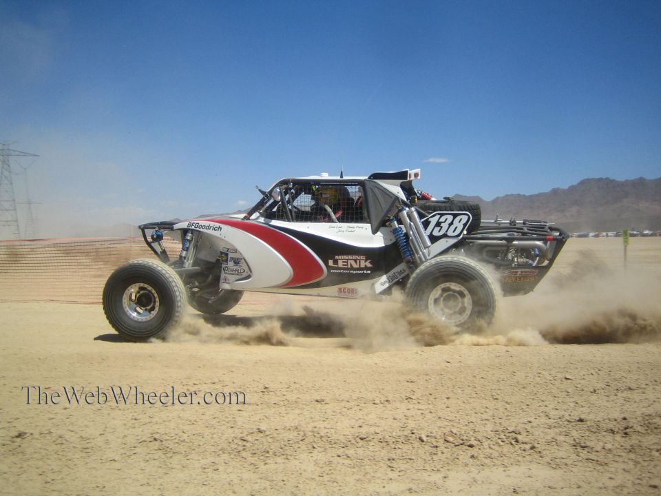 White black and red off-road race buggy number 138 jumping in the desert