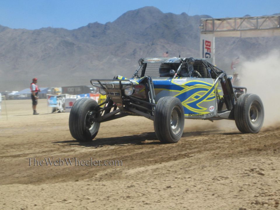 Silver blue and yellow open tube-chassis off-road buggy racing in the desert