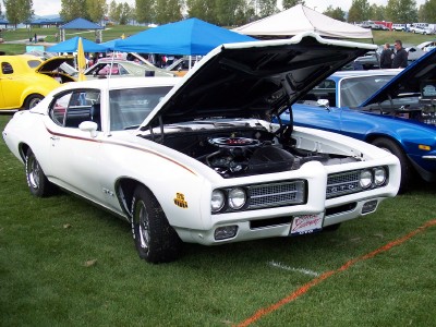 1972 Ford Ranchero - A white 1970 Pontiac GTO is displayed with its hood open at an outdoor car show.