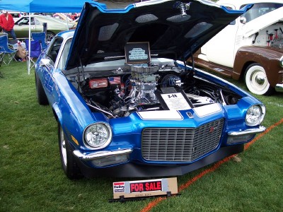 1972 Ford Ranchero - A blue Chevrolet Camaro Z-28 is displayed with its hood open, revealing a powerful engine, at an outdoor car show.