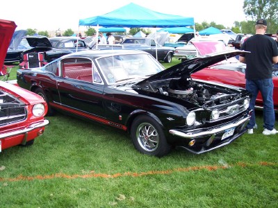 1972 Ford Ranchero - A black 1965 Ford Mustang is displayed with its hood open at an outdoor car show.