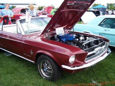 1972 Ford Ranchero - A maroon 1967 Ford Mustang convertible is displayed with its hood open, revealing the engine and a sign that reads "67 PONY".