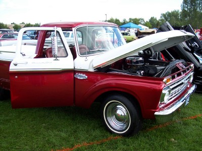 1972 Ford Ranchero - A classic red and white Ford pickup truck is displayed with its hood open at an outdoor event.