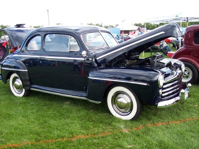 1972 Ford Ranchero - A dark blue 1946 Ford coupe is displayed with its hood open at an outdoor car show.