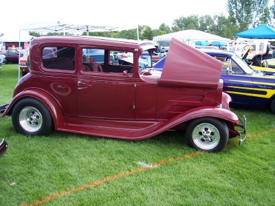 1972 Ford Ranchero - A maroon coupe hot rod is displayed on a grassy field with its hood open, alongside other vehicles.