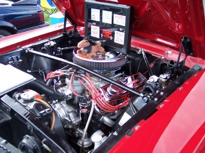 1972 Ford Ranchero - The engine bay of a red vehicle is open, revealing its components and a decorative stuffed horse.