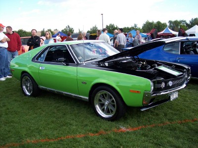 1972 Ford Ranchero - A bright green 1970 AMC AMX is displayed with its hood up at an outdoor car show, alongside other vehicles.